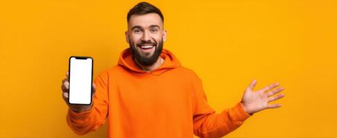 The enthusiastic man showcasing a smartphone against a vibrant orange background. photo