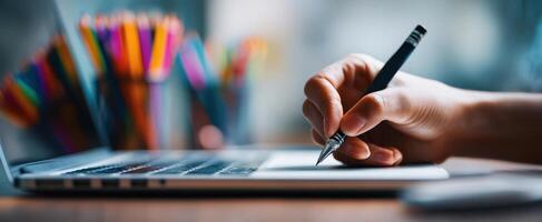 The hand writing notes on a laptop in a creative workspace. photo