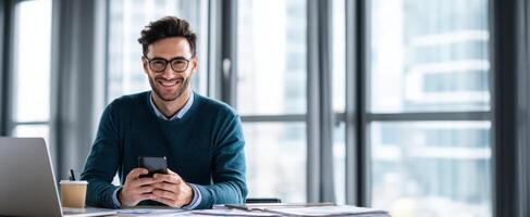 The smiling young man using a smartphone in a modern office environment. photo