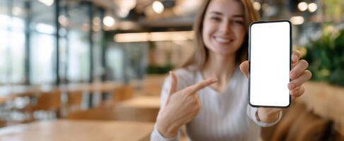 The woman displays a smartphone screen while smiling in a modern cafe. photo