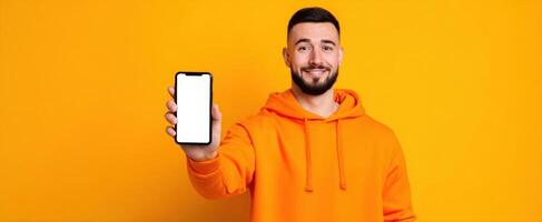 The smiling man showcasing a smartphone against a vibrant orange background photo