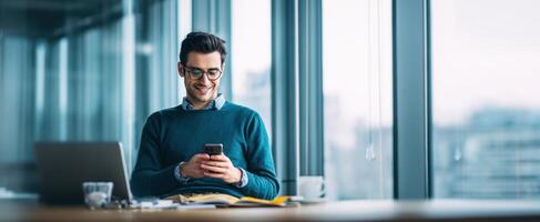 The young man smiles while using his smartphone in a modern office. photo