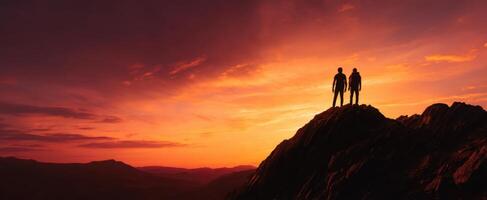 The hikers standing on a mountain peak during a vibrant sunset. photo