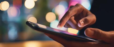 The smartphone in hand illuminated by soft bokeh lights at night. photo