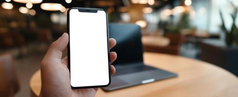 The smartphone held in hand with a blank screen in a modern workspace. photo