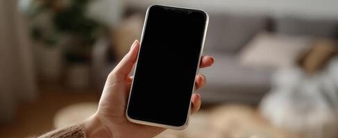 The Smartphone Held in a Hand Against a Cozy Indoor Background photo