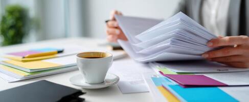 The professional workspace with coffee and assorted paperwork arranged neatly. photo