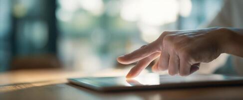 The hand interacting with a touchscreen tablet in a modern work environment. photo