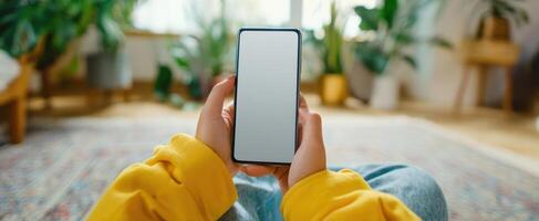 The hands holding a smartphone in a cozy indoor setting with plants. photo