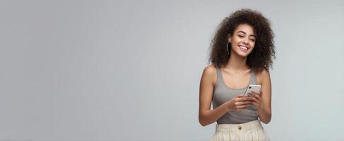 The woman smiling and using a smartphone in a casual setting. photo