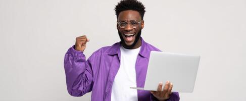 The joyful man celebrating success while using a laptop in a modern workspace. photo