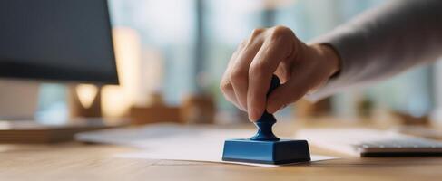 The hand applying a blue stamp on official documents in a modern office setting photo