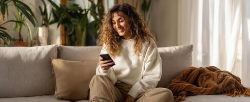 The woman smiling while using her smartphone on a cozy couch. photo