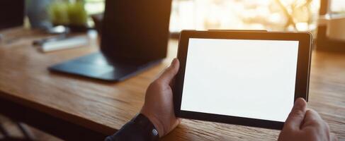The modern tablet held in hands with a blank screen in an office setting. photo