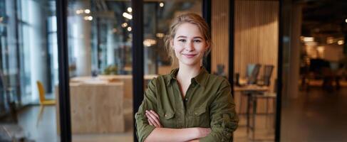 The confident young woman in a modern office setting smiling proudly. photo
