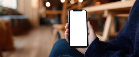 The smartphone held in a cozy cafe setting with a blank screen. photo