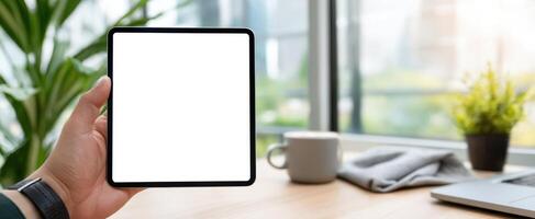 The tablet displayed in a modern workspace with plants and coffee. photo