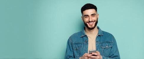 The smiling man holding a smartphone against a vibrant blue background. photo
