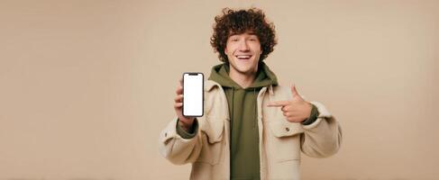 The young man proudly showcasing his smartphone against a neutral background. photo
