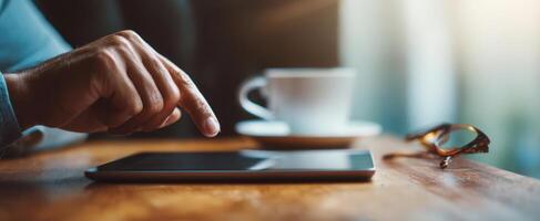The hand interacts with a tablet while enjoying a coffee in a cozy setting. photo