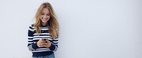 The woman smiling while texting on her phone against a minimalist background. photo