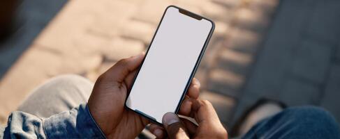 The smartphone displaying a blank screen held by casual person outdoors. photo