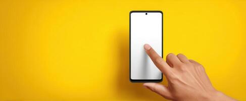 The smartphone being touched by a hand on a vibrant yellow background. photo