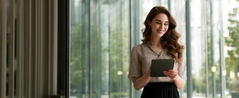The young woman happily using a tablet in a modern office space. photo