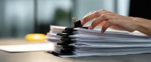 The Organized Stack of Paperwork with a Hand Holding a Binder Clip. photo