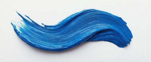 The vibrant blue paint stroke creating a flowing artistic wave on canvas. photo