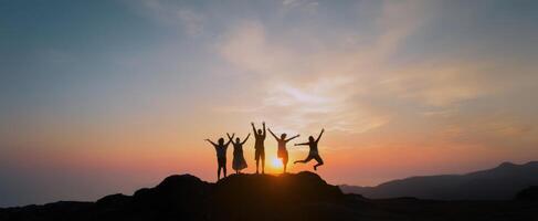 The joyful group celebrating life at sunset on a mountain top. photo