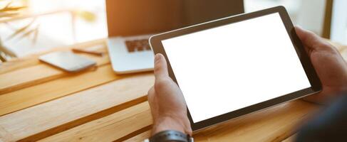 The tablet held in hands showcasing a blank screen in a modern workspace. photo