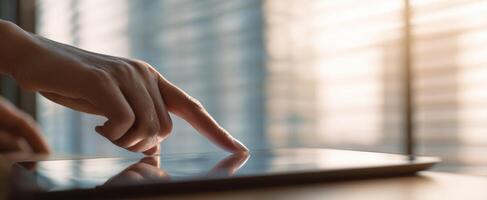 The hand interacting with a touchscreen tablet in a modern workspace setting. photo