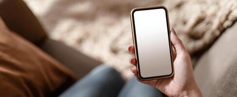 The smartphone held in a relaxed hand on a cozy couch photo