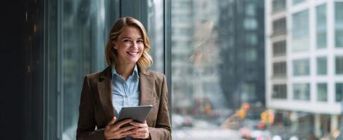 The professional woman smiling while using a tablet in a modern urban office. photo