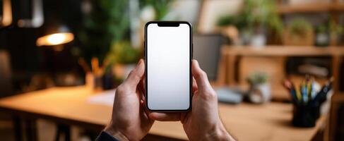 The smartphone held in hands against a stylish home office background with plants. photo
