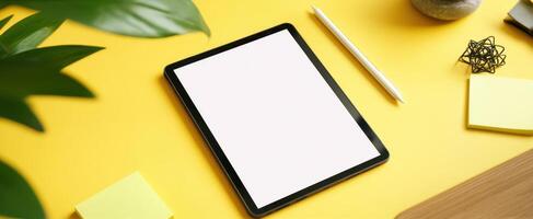 The modern tablet and stationery on a vibrant yellow workspace. photo