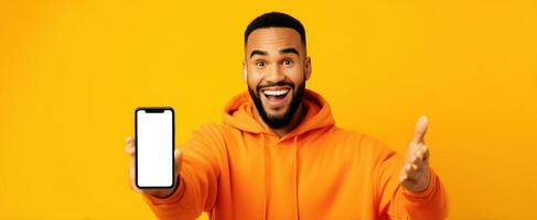 The man proudly displaying a smartphone against a vibrant yellow background. photo