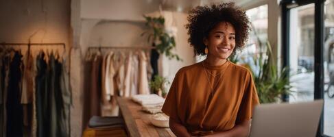 The woman in a boutique smiles while working on her laptop. photo