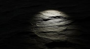 A dark rock surface with a light shining through it photo