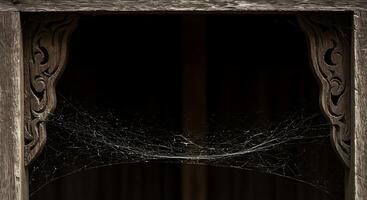 A spider web is hanging from a wooden window photo