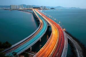 Illuminated Highway Bridge Over Calm Sea At Night With City View photo