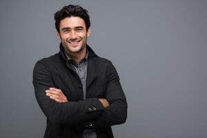 A happy and smiling man wearing a black coat with arms crossed photo