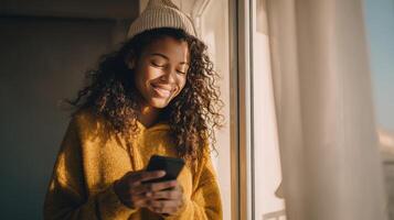 Beautiful Woman Smiling Brightly While Using Her Phone Near the Window photo