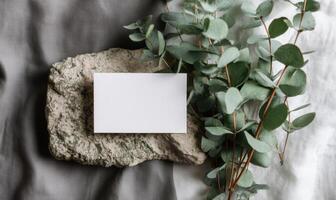 Blank Business Card Mockup on Stone with Eucalyptus Branches and Fabric photo