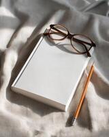 Still Life Composition Of Notebook Glasses and Pencil On Shiny Fabric photo