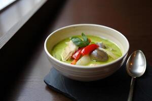 A bowl of soup with a spoon sitting on a table photo