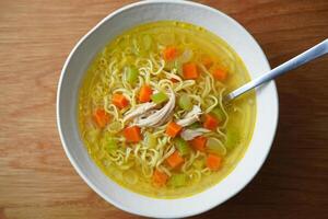 A bowl of chicken noodle soup with carrots and celery photo