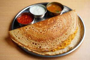 A plate with a crepe and some sauces on it photo