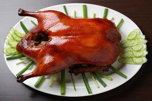 A large roasted duck on a plate with cucumbers photo